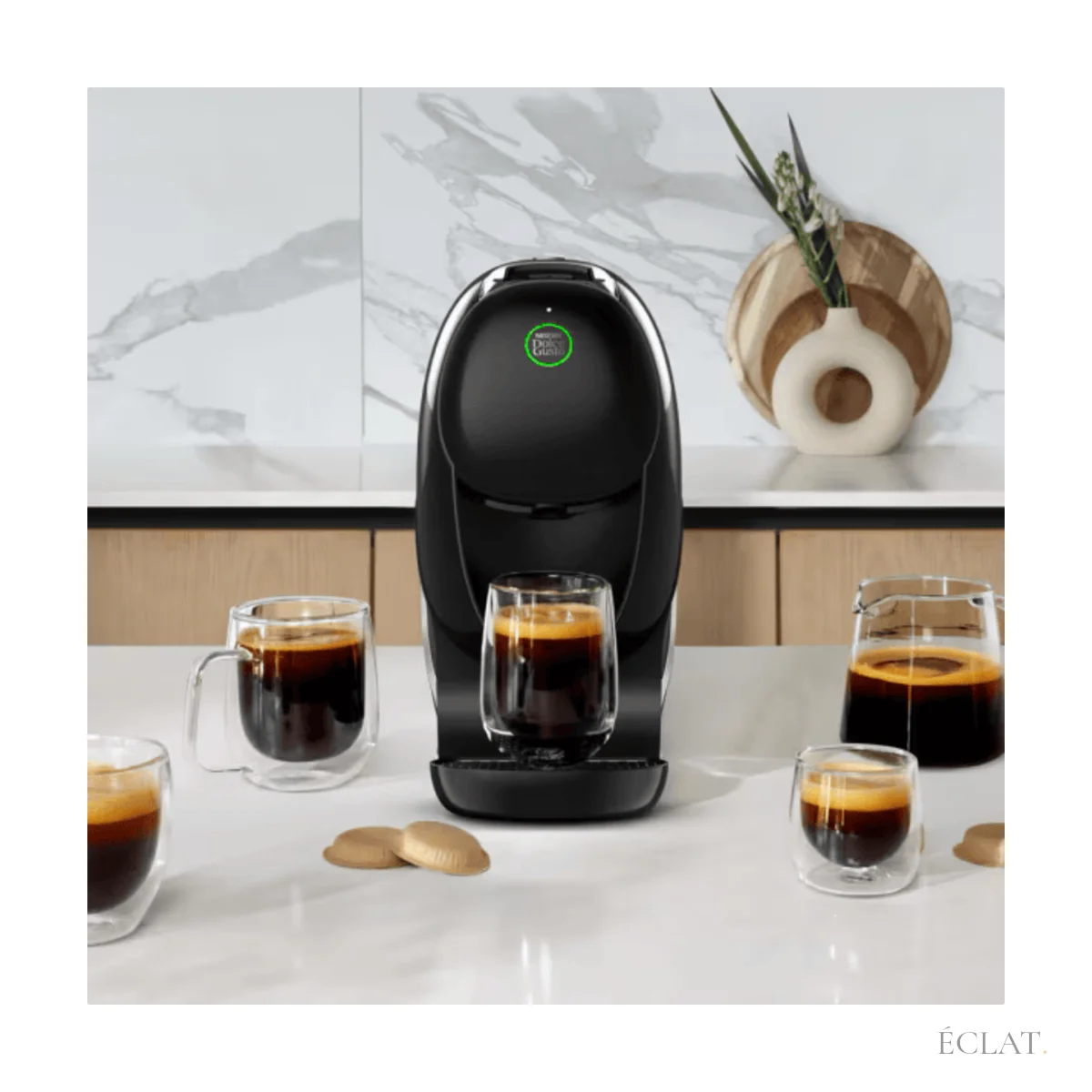 Machine à café à dosettes sur un plan de travail, cafés servis en tasses de verre
