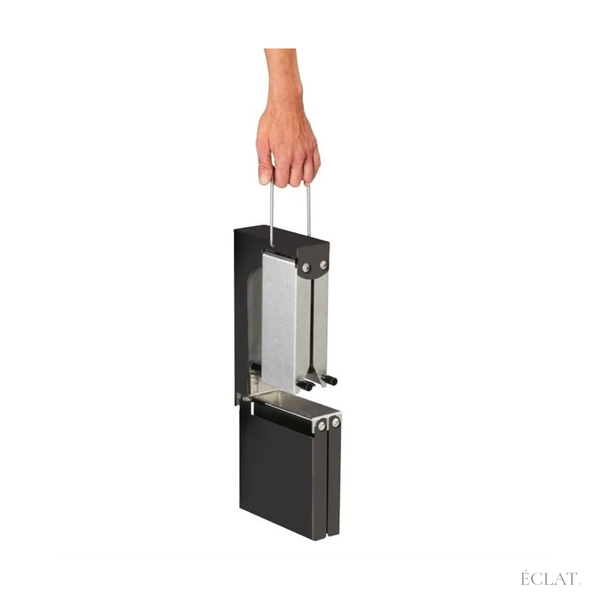 Appareil à raclette replié et porté à la main par sa poignée, vu de côté