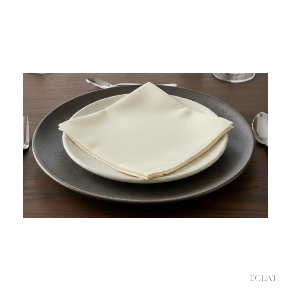 Serviette ivoire pliée en pointe sur une assiette, table dressée