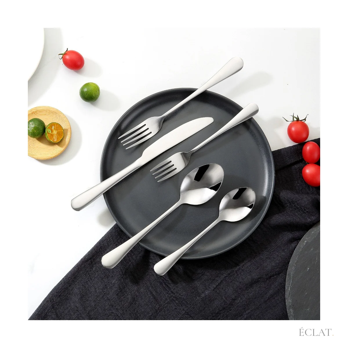 Couverts inox posés sur une assiette noire, table dressée