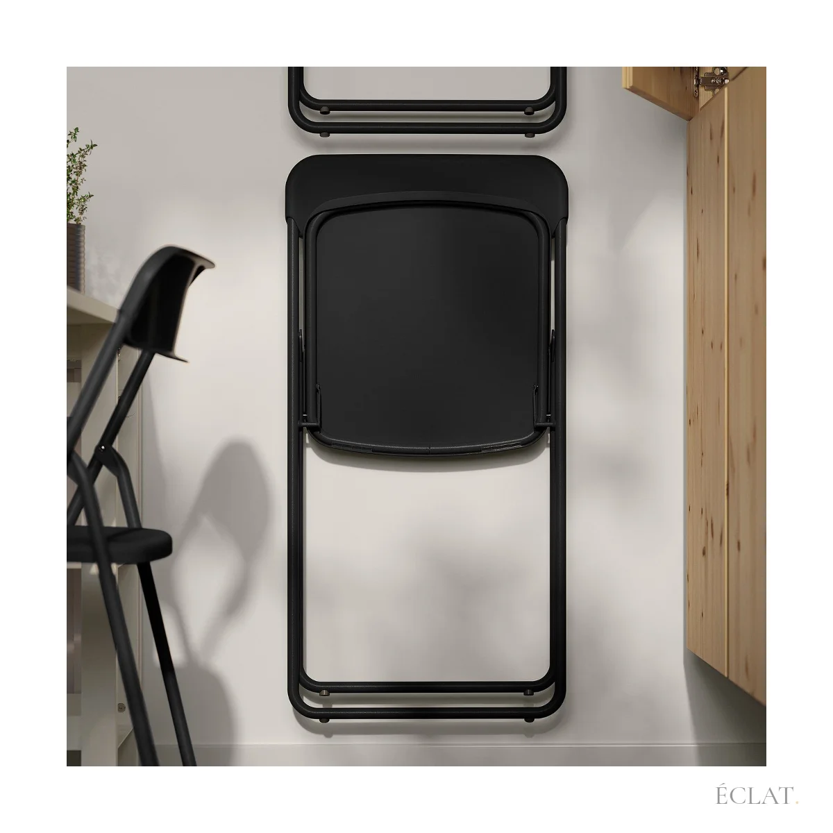 Chaises pliantes noires repliées à plat, suspendues contre un mur pour gagner de la place