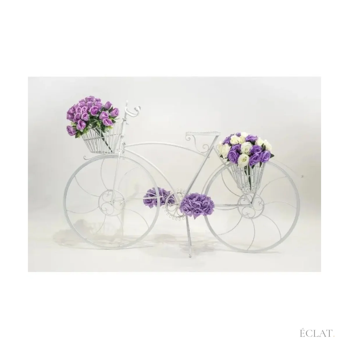 Location vélo décoratif blanc en métal, paniers garnis de fleurs violettes