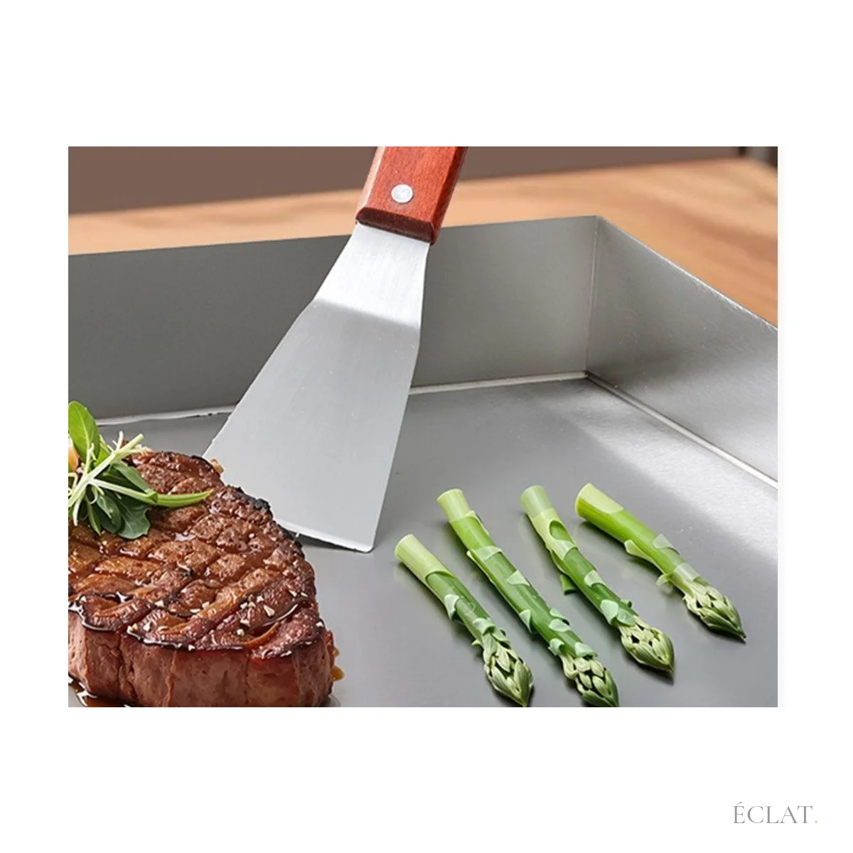 Spatule sur la plaque en acier d'une plancha, steak et asperges