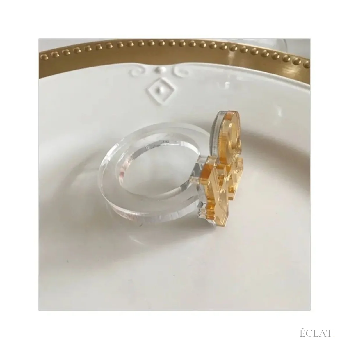 Anneau transparent du rond de serviette posé sur une assiette blanche