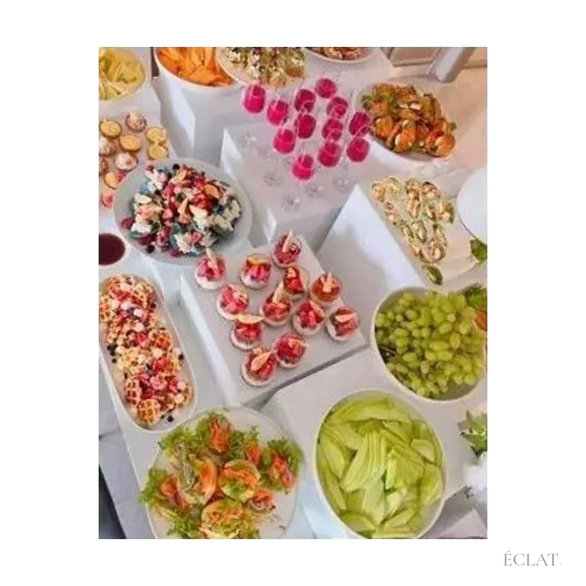 Buffet de cocktail étagé sur des cubes blancs : verrines, fruits et petits fours