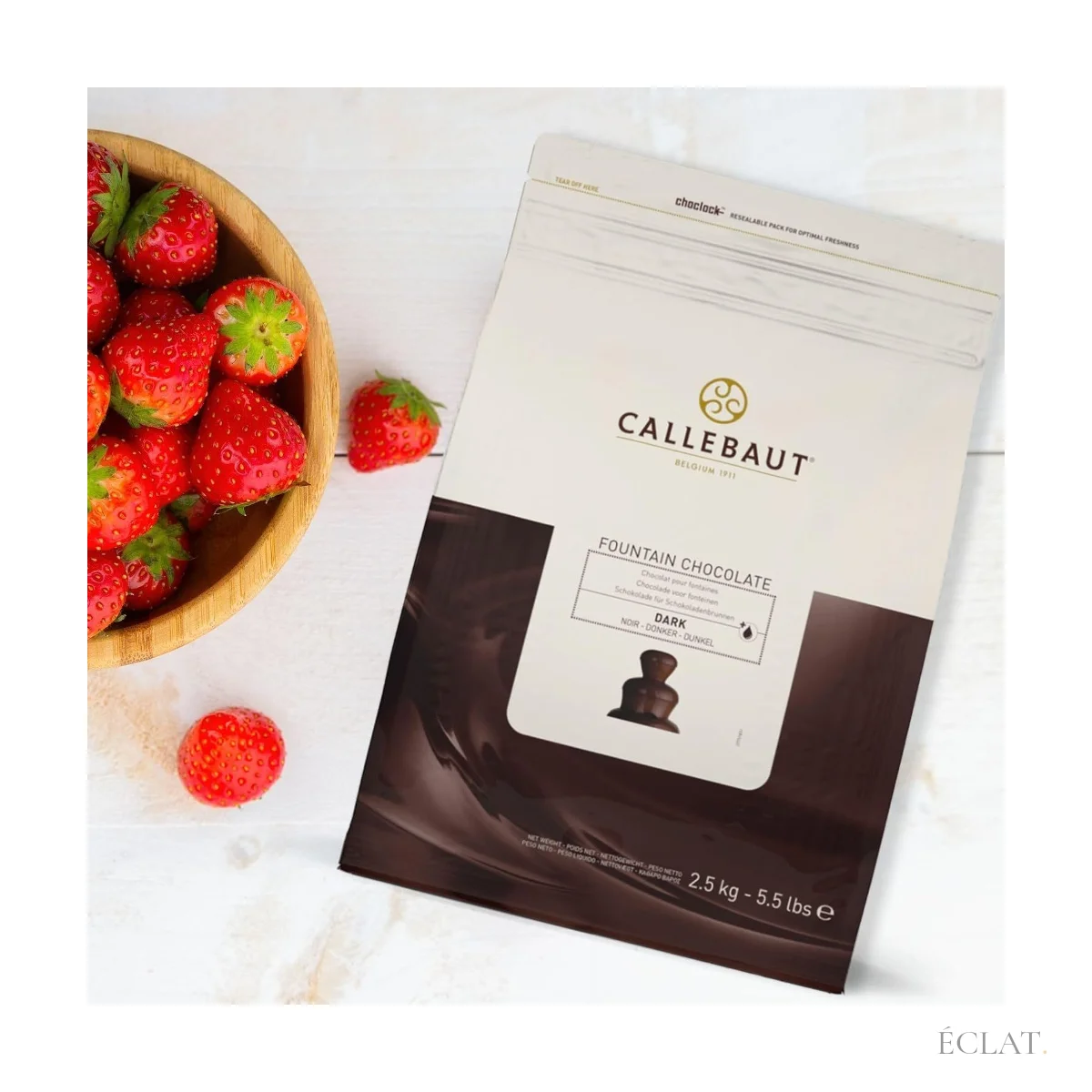 Sac de chocolat noir pour fontaine Callebaut posé à côté d'une coupe de fraises