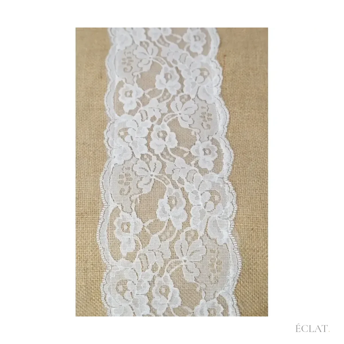 Détail de la dentelle blanche à motifs floraux cousue sur la toile de jute du chemin de table