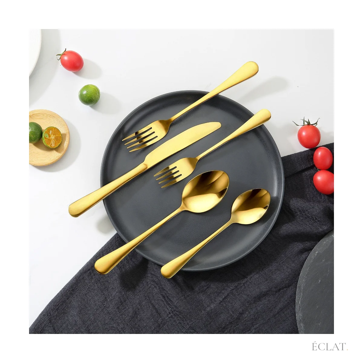 Couverts dorés posés sur une assiette noire, table dressée